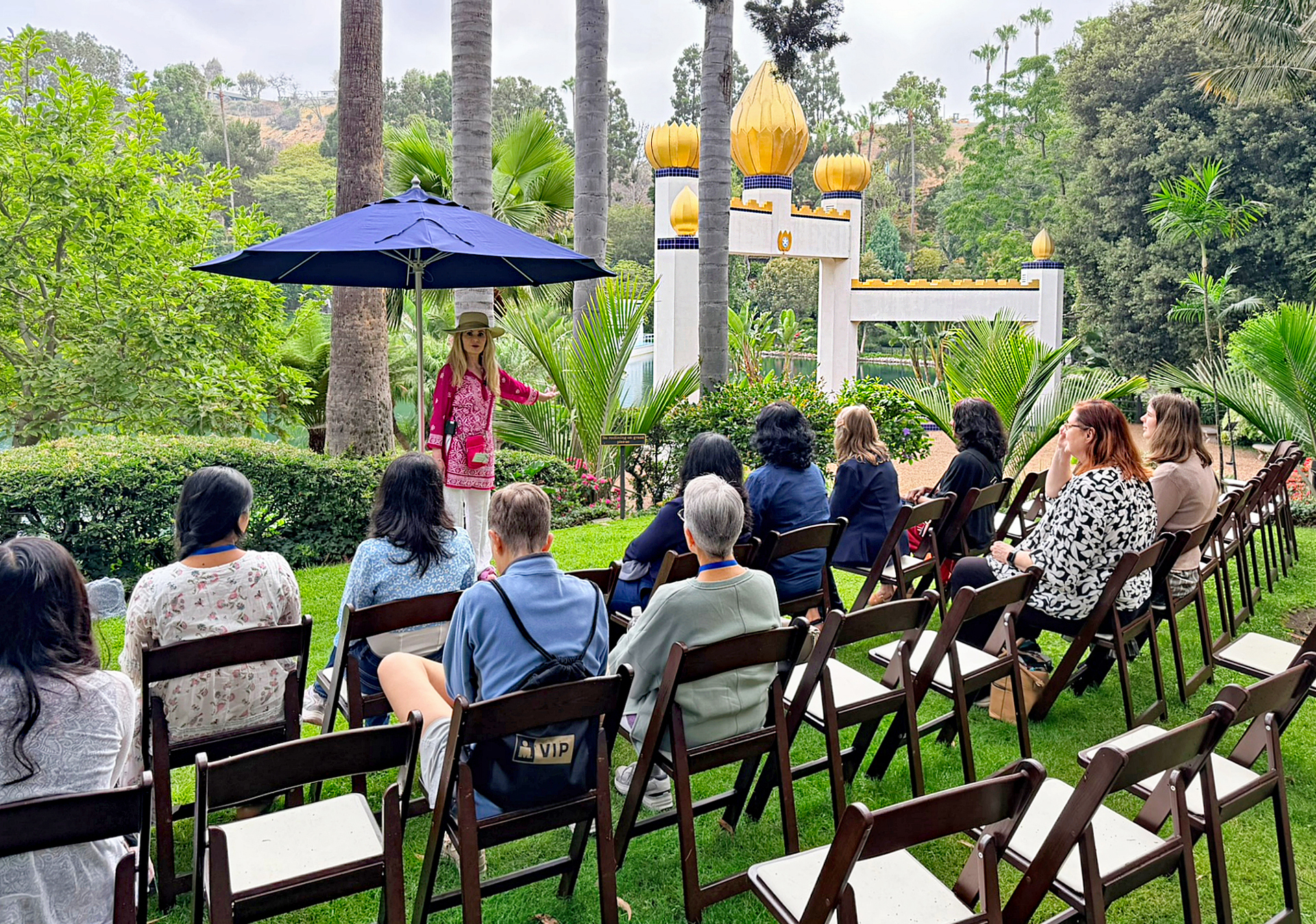 A volunteer shares the history of the Lake Shrine, with the Golden Lotus Archway in the background. This sacred site was re-opened this year after being closed due to the 2025 Palisades Fire.