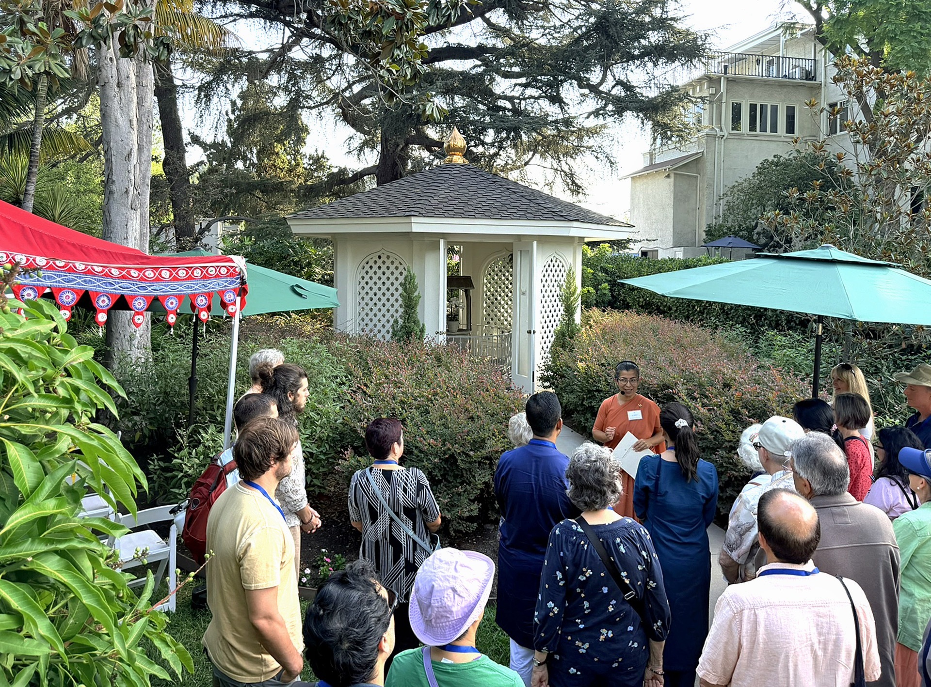 The guests learn about the 100-year history of Mother Center by the Wishing Well mandir.