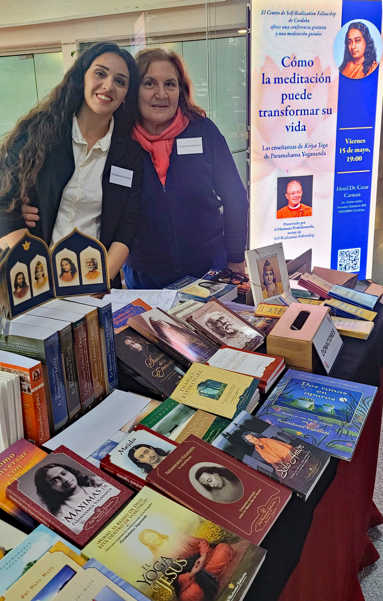 Joyous Cordoba volunteers at the book table displaying SRF publications and devotional items.