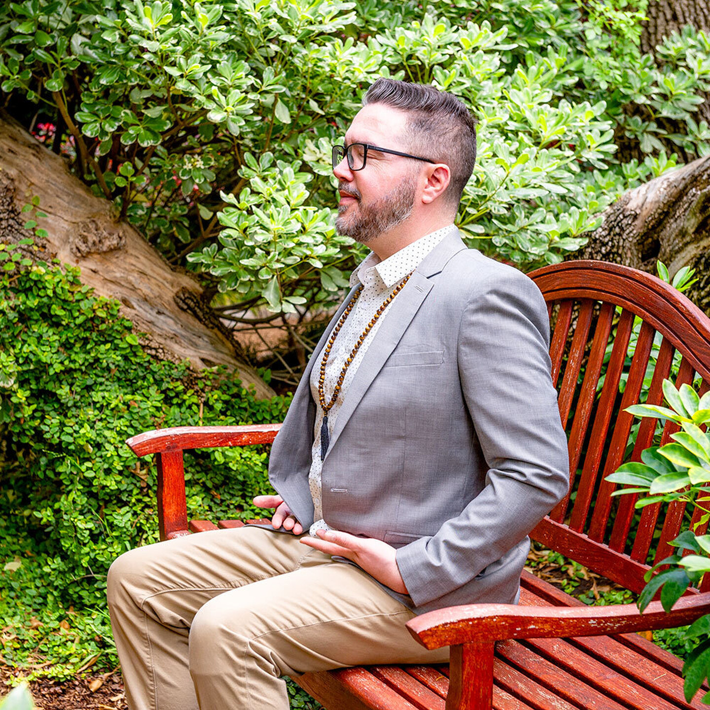 Devotee meditating in garden sitting on bench square